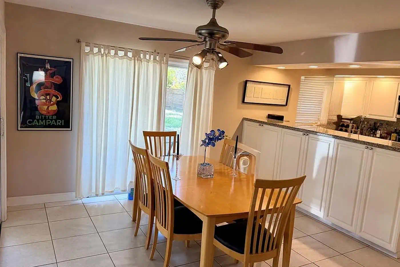 Bright dining area with sliding glass doors, tiled floors and adjacent kitchen at 5281 Teak Wood Drive, Logan Woods, Naples FL