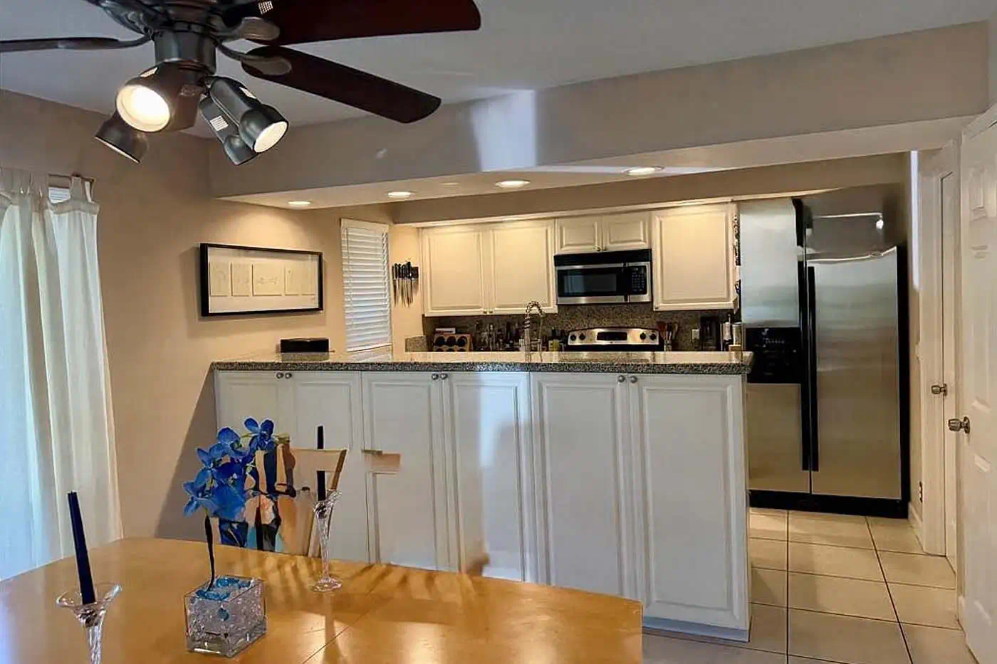 Open kitchen with white cabinetry, granite countertops and stainless steel appliances at 5281 Teak Wood Drive, Logan Woods, Naples FL