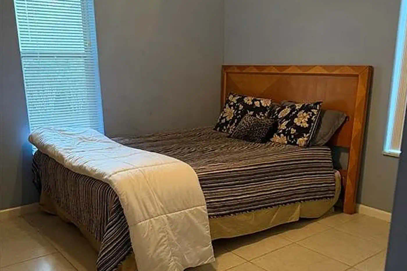 Cozy bedroom with natural light, tiled floors and window view at 5281 Teak Wood Drive, Logan Woods, Naples FL