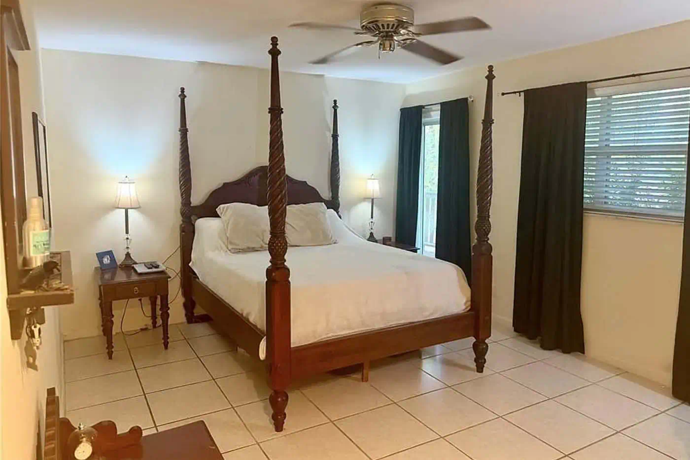 Primary bedroom with four-poster bed, tiled floors, ceiling fan and natural light at 5281 Teak Wood Drive, Logan Woods, Naples FL
