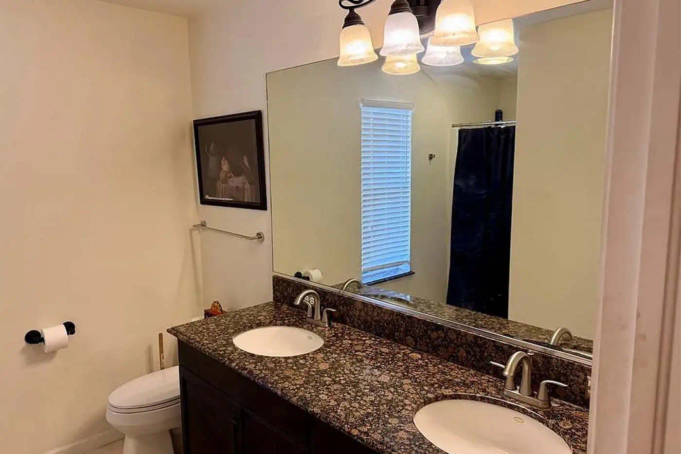 Bathroom with dual sink granite vanity, large mirror, modern lighting and shower at 5281 Teak Wood Drive, Logan Woods, Naples FL