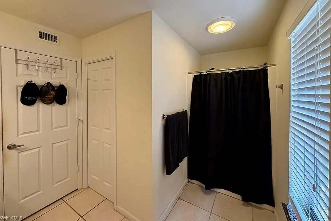 Guest bathroom with shower, tiled floors, window blinds and storage doors at 5281 Teak Wood Drive, Logan Woods, Naples FL