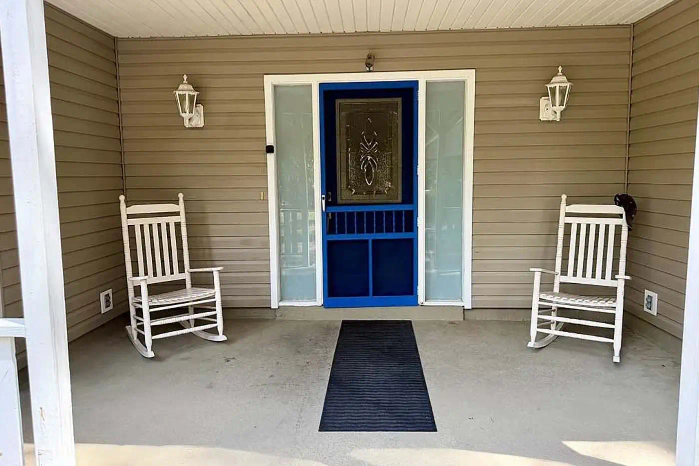 Front porch with blue entry door, rocking chairs and covered entrance at 5281 Teak Wood Drive, Logan Woods, Naples FL